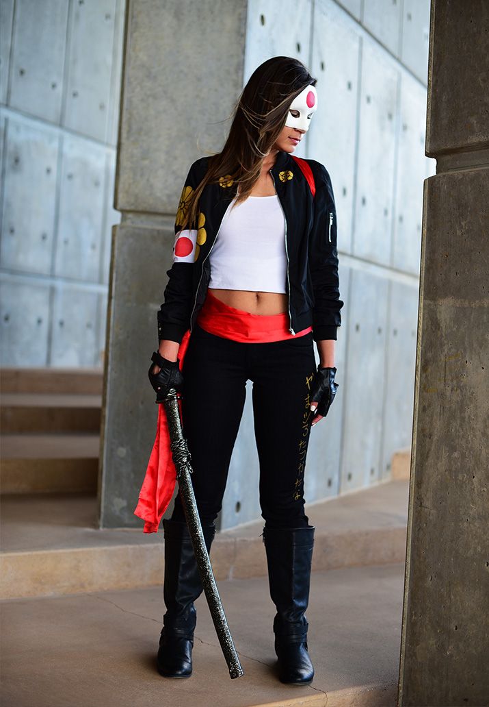 a woman in black and white outfit holding a baseball bat next to a building with concrete walls