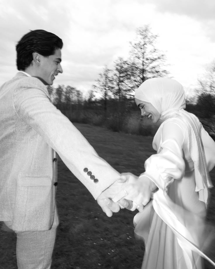 a man and woman holding hands in the grass