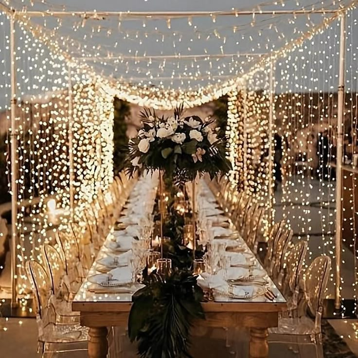 a long table with white flowers and greenery is set up for a formal dinner