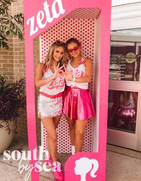 two girls standing in front of a pink sign with the word zeda on it