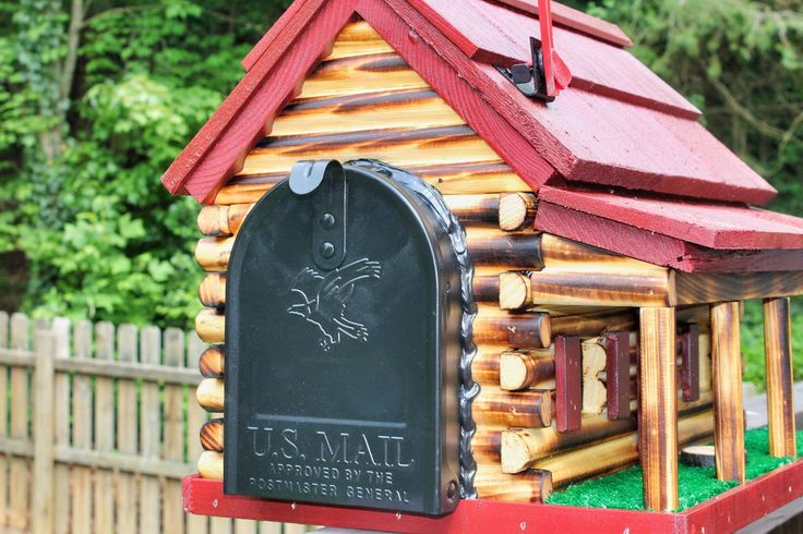 a mailbox with a bird on it in front of a wooden fence and trees