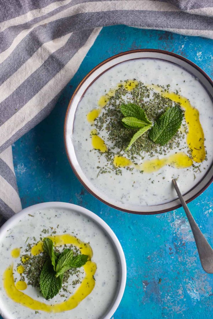 two bowls filled with yogurt and topped with fresh mint garnishments