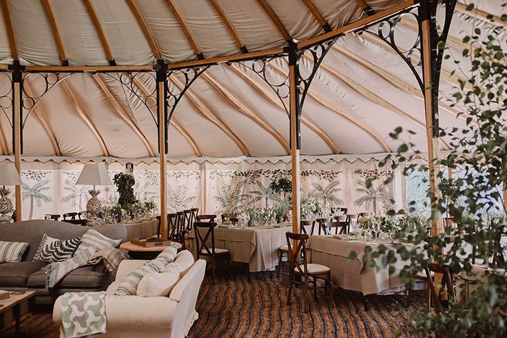 a living area with couches, tables and chairs under a large tented roof