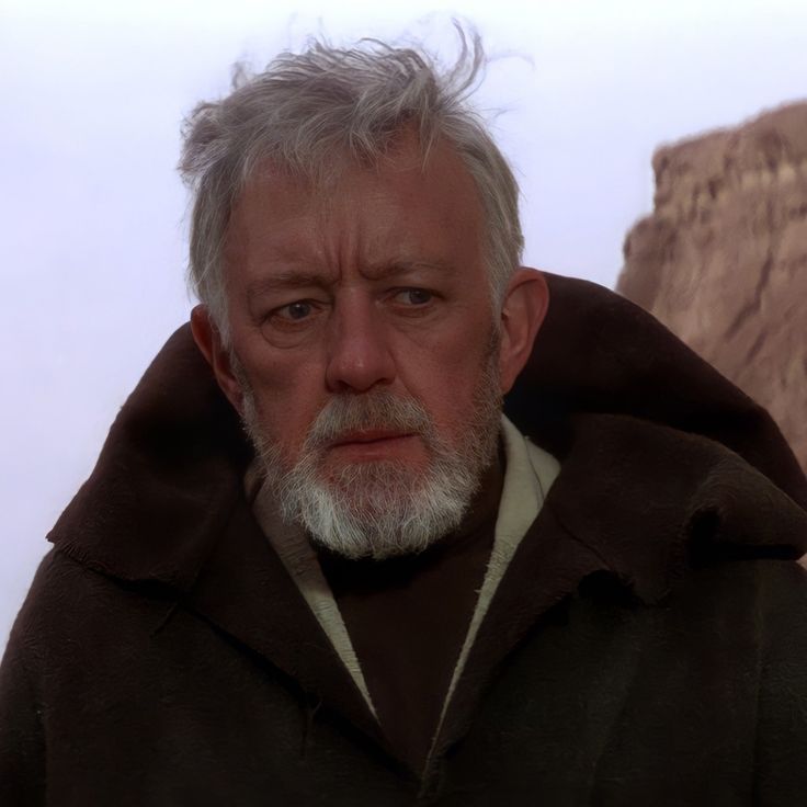 an older man with white hair and beard wearing a brown jacket looking at the camera