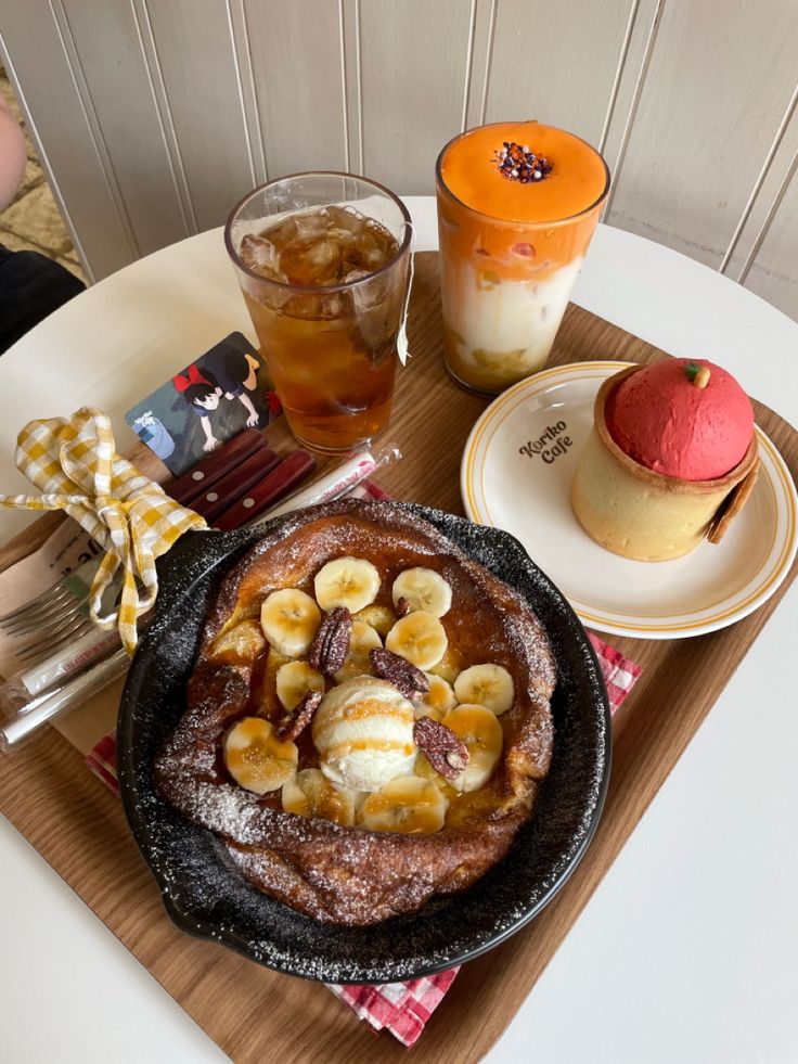 a pancake with banana slices and other desserts on a wooden tray at a restaurant