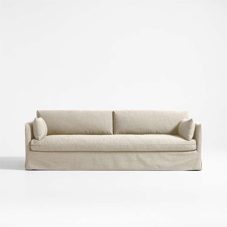 a white couch sitting on top of a white floor next to a wall with a light colored background