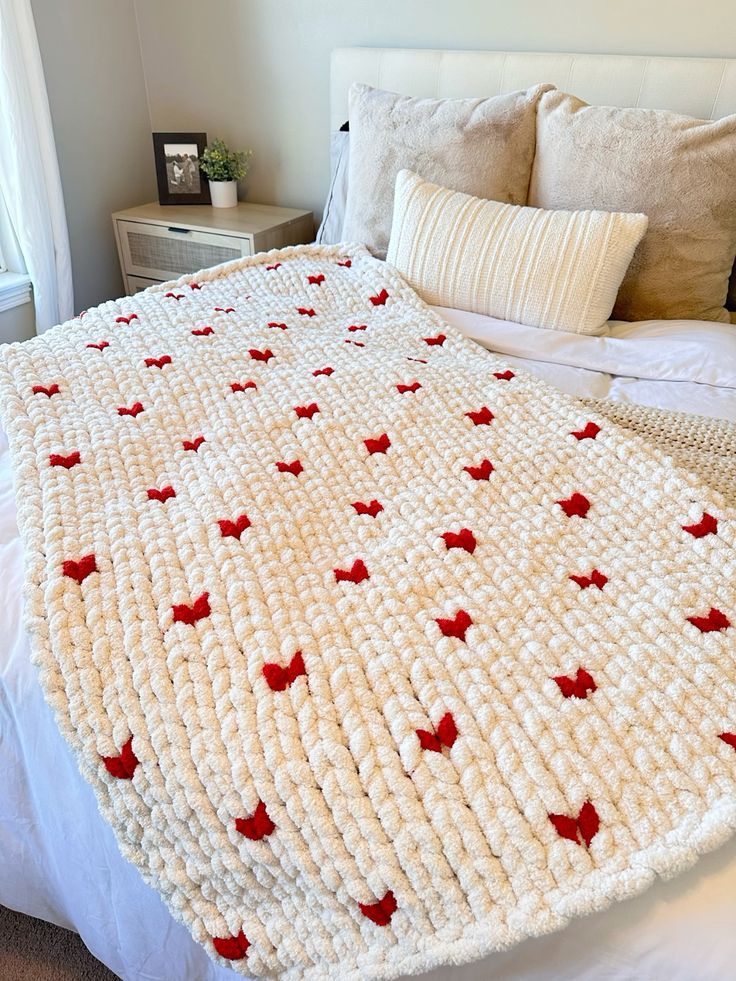 a crocheted blanket on top of a bed next to pillows and a night stand