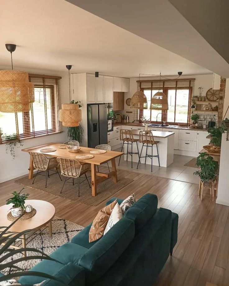 a living room filled with furniture next to a kitchen and dining room table on top of a hard wood floor