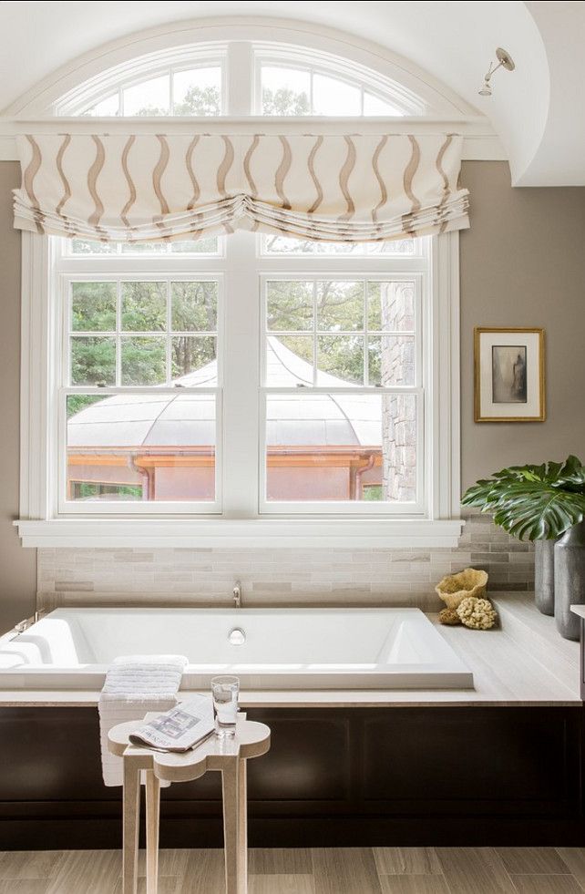 a bath tub sitting under a window in a bathroom