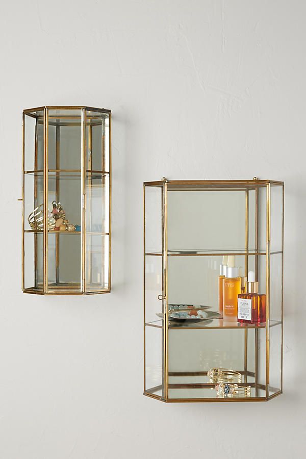 two glass shelves with candles and other items in them on the wall next to each other