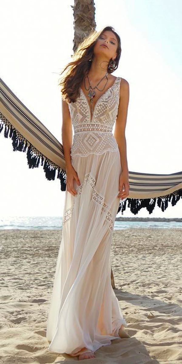 a beautiful woman standing on top of a sandy beach next to a hammock