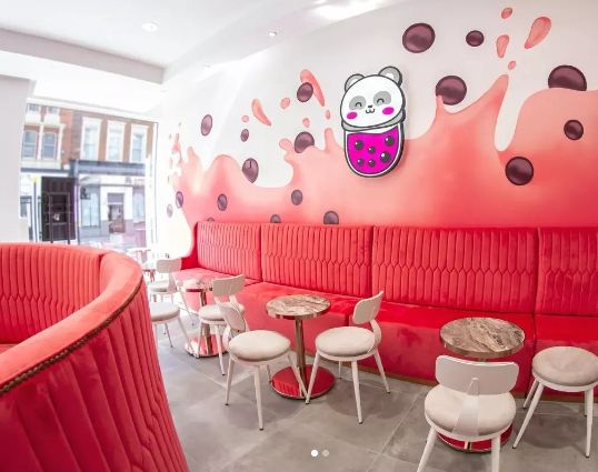 the interior of a restaurant with red booths and white chairs, decorated with cartoon characters