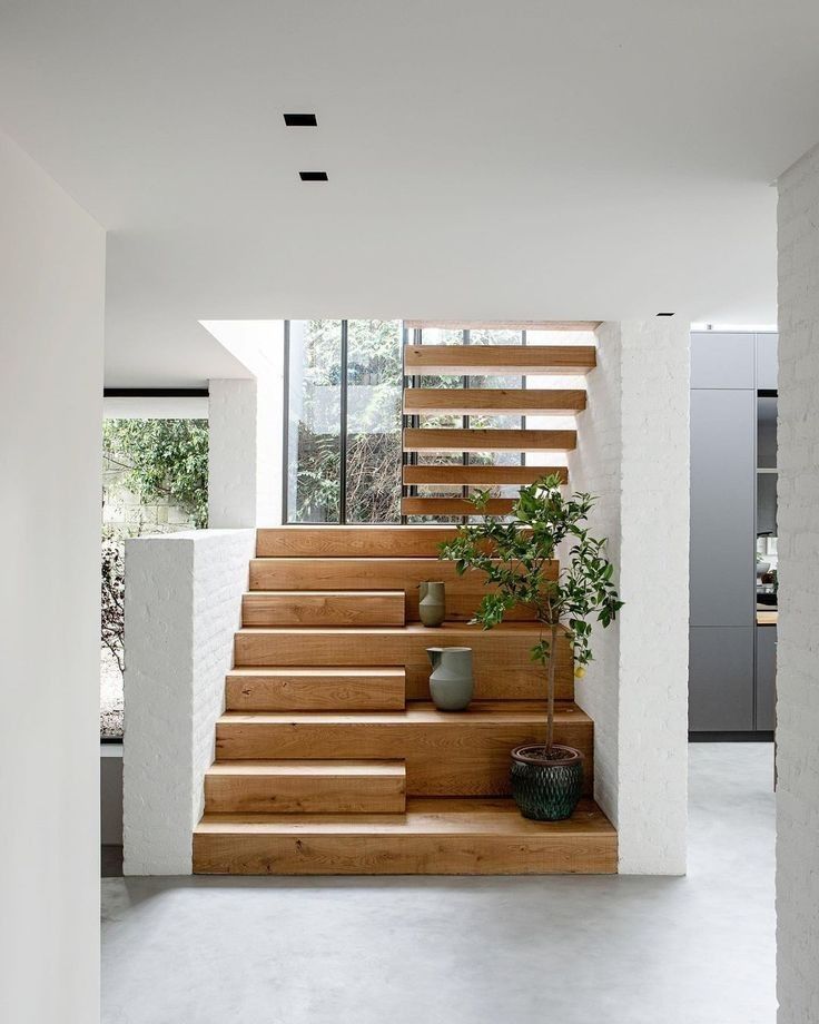 the stairs in this modern house are made of wood and white concrete, with planters on each side