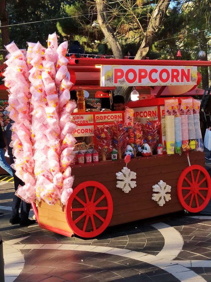 a popcorn cart is decorated with pink candy