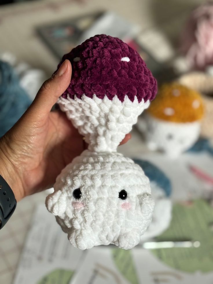 a hand is holding up a crocheted stuffed animal that looks like an ice cream cone