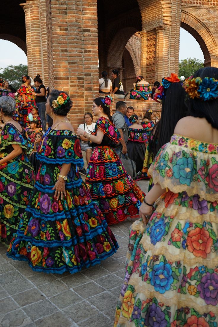 several women in colorful dresses are dancing together