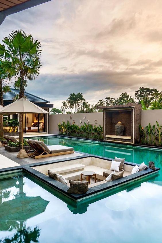 an outdoor swimming pool with lounge chairs and umbrellas