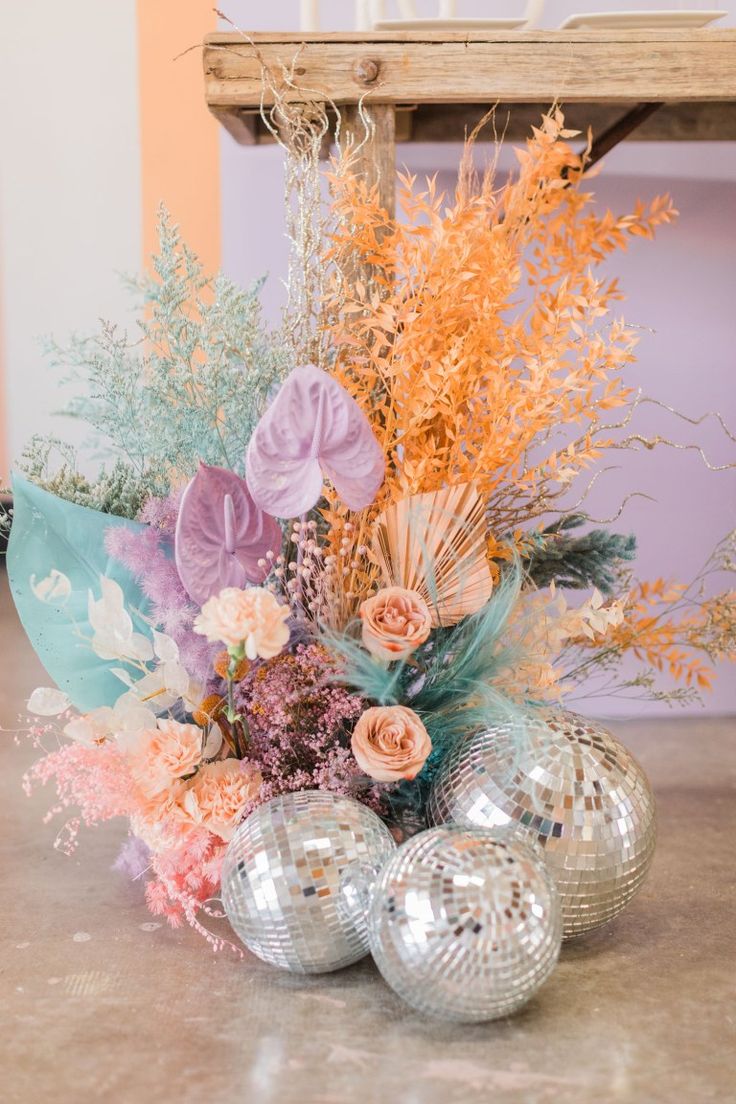 an arrangement of flowers and disco balls on a table