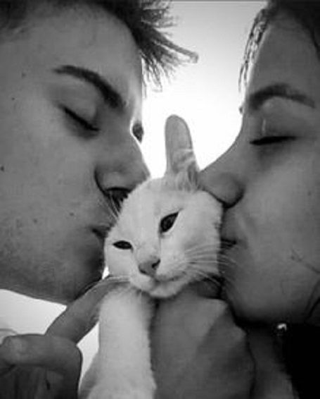 a man kissing a woman while holding a white cat