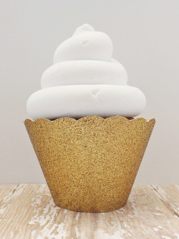 a cupcake topped with white frosting on top of a wooden table