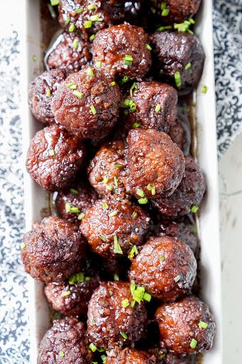 meatballs in a white dish with parsley on top