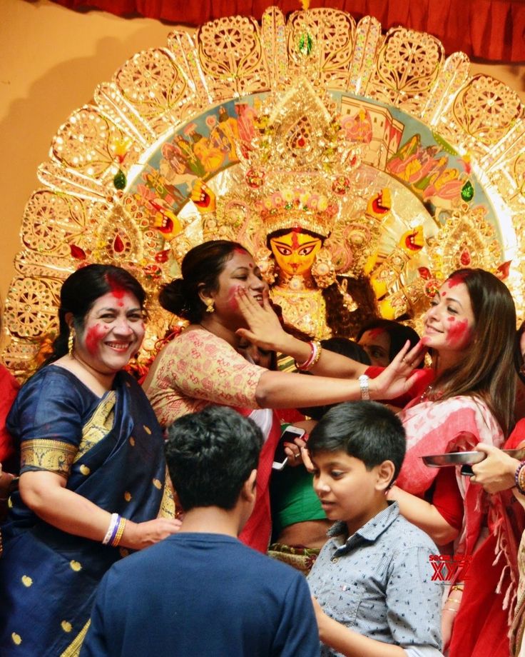 a group of people standing around each other in front of a decorated display with gold and red decorations