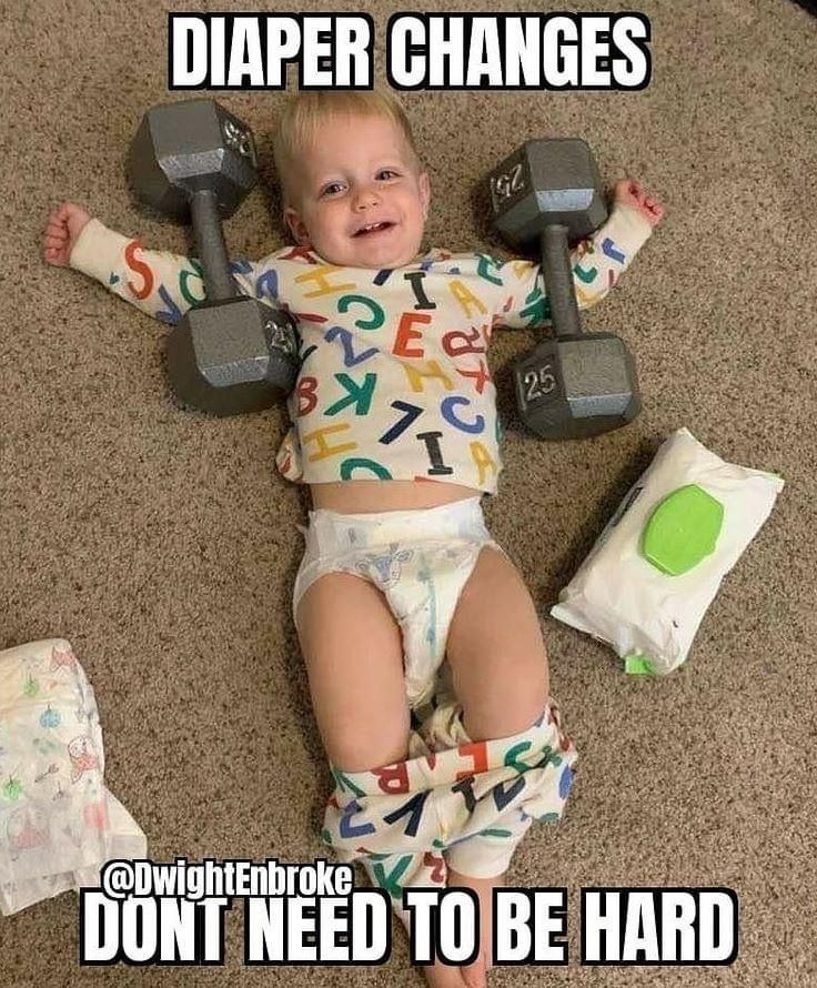 a baby laying on the floor with two dumbbells and diapers around him