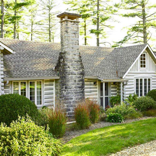 an old log cabin sits in the middle of a wooded area with trees and shrubs