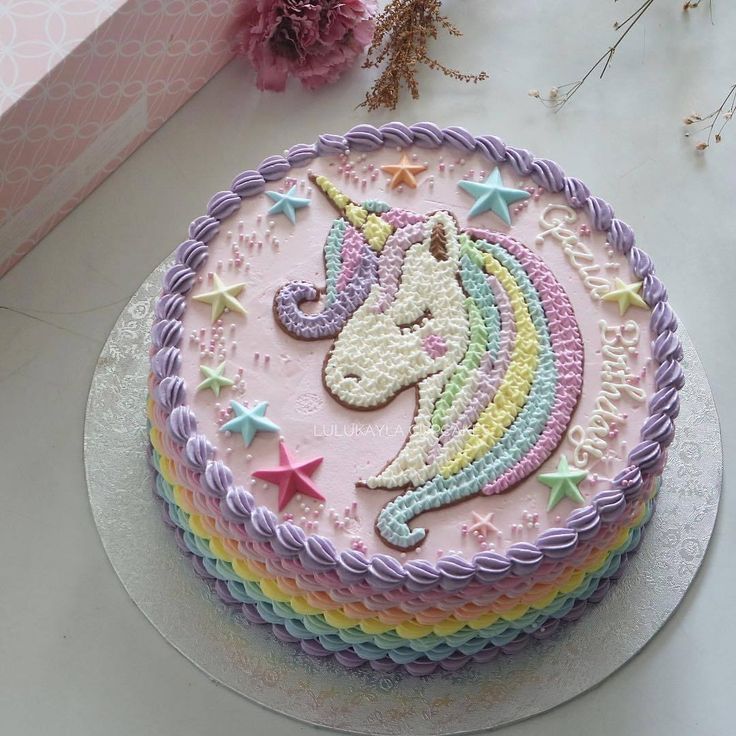 there is a cake decorated with a rainbow unicorn on the top and stars around it