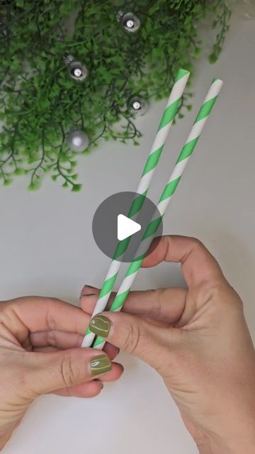 two hands holding green and white striped straws