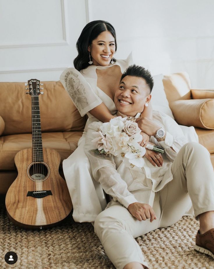 a bride and groom sitting on the floor next to a guitar