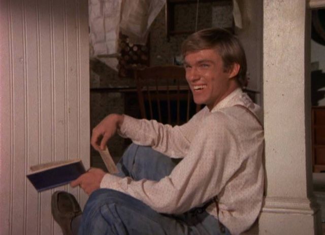 a man sitting on the floor with his legs crossed and holding a book in front of him