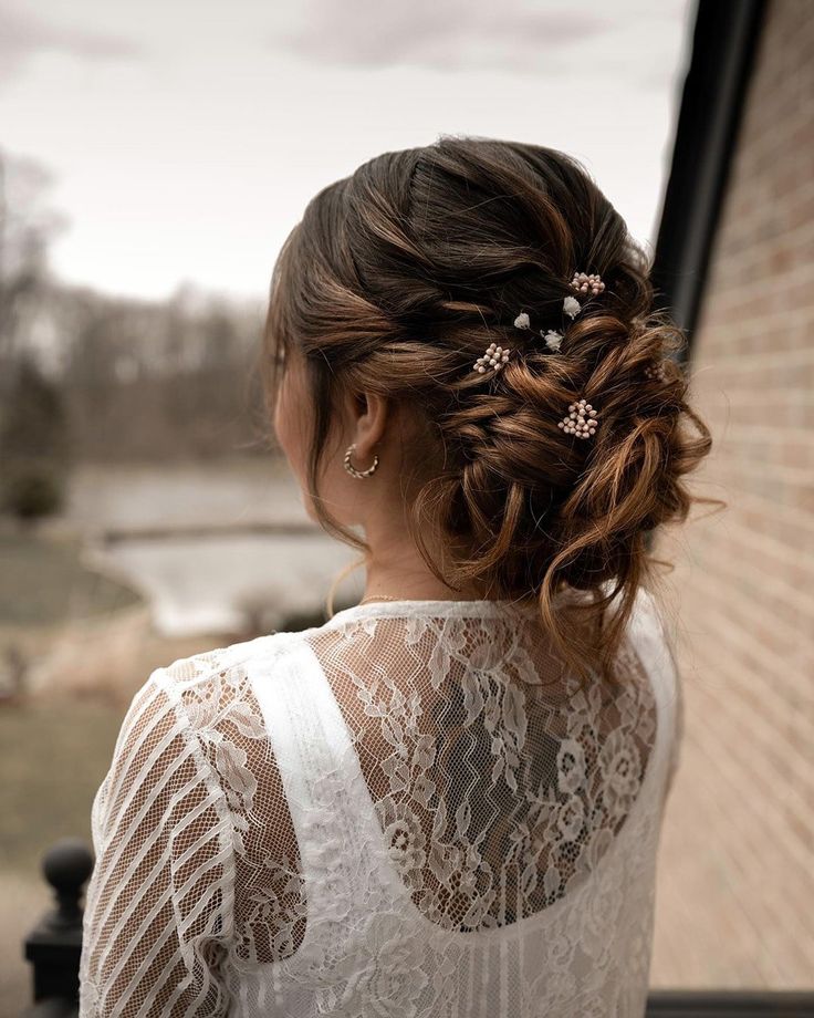 a woman with long hair wearing a white top and some flowers in her hair is looking out the window