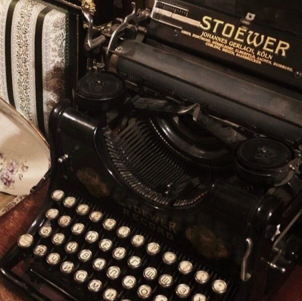 an old fashioned typewriter sitting on top of a wooden table next to other items