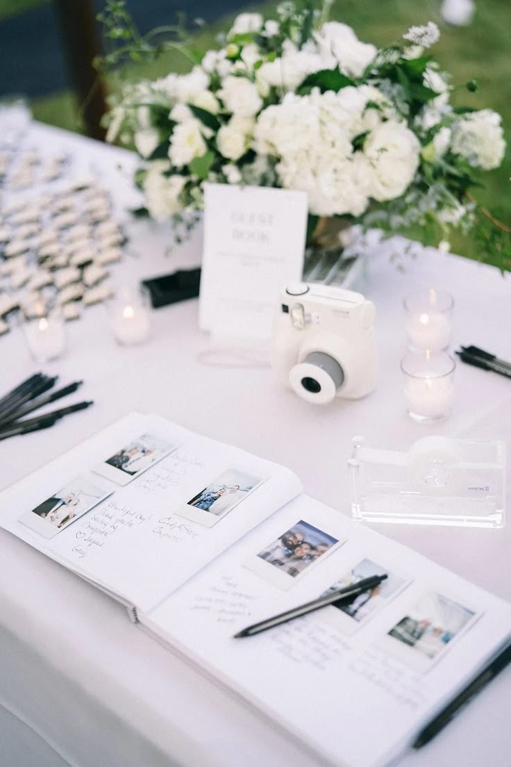 an open book sitting on top of a table next to a bouquet of white flowers