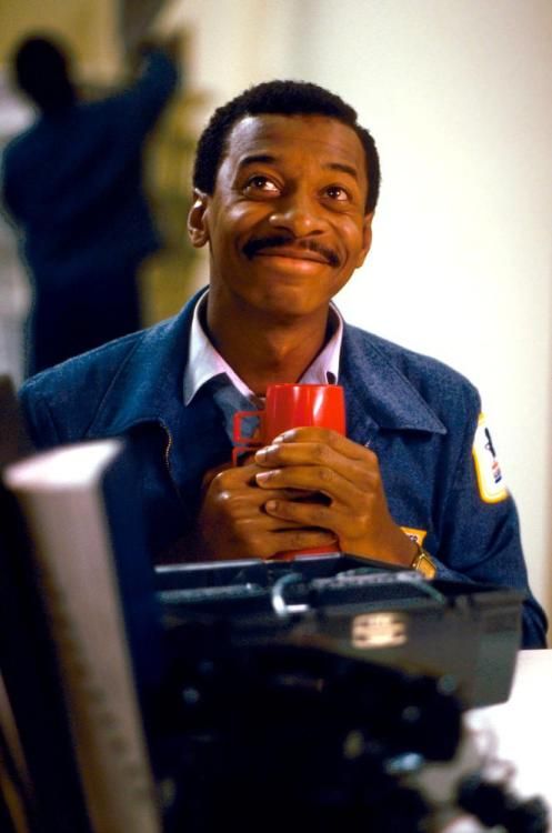 a man holding a red cup in his right hand while sitting at a computer desk