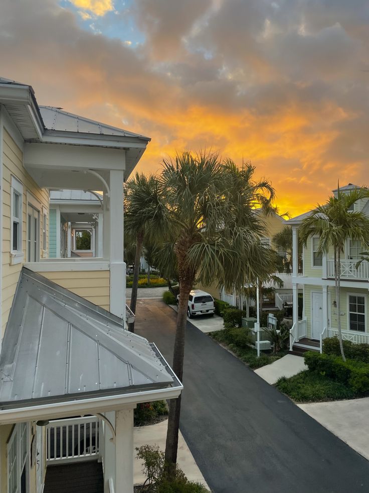 the sun is setting over some houses and palm trees