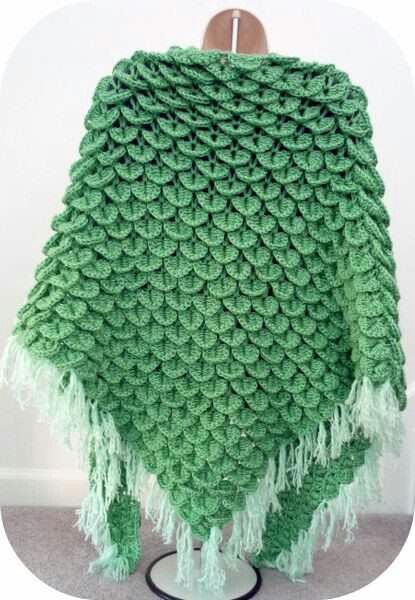 a green crocheted blanket sitting on top of a wooden chair