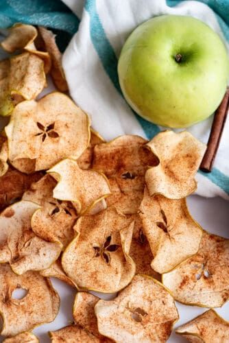 an apple and cinnamon chips on a white plate