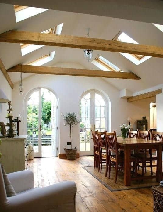 an open living room and dining area with wooden floors, vaulted ceilings, and white walls