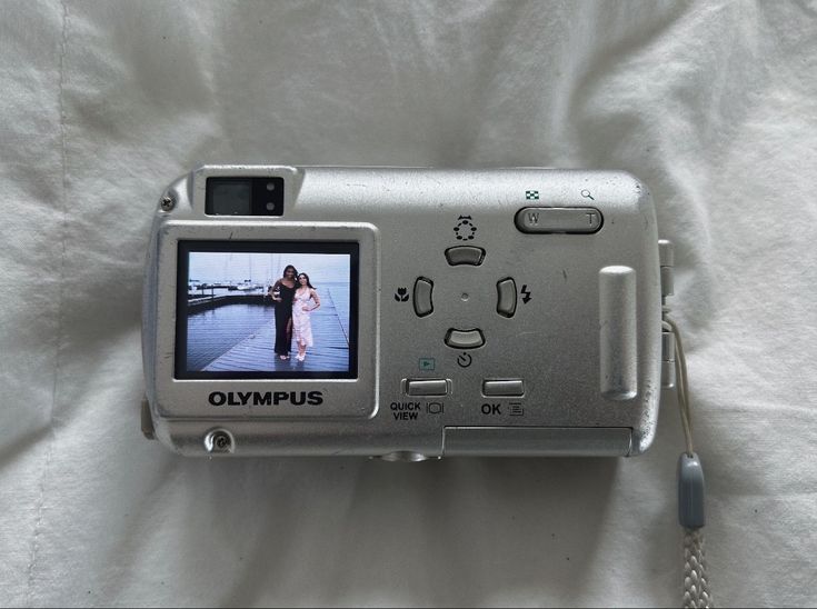 a silver camera sitting on top of a white sheet