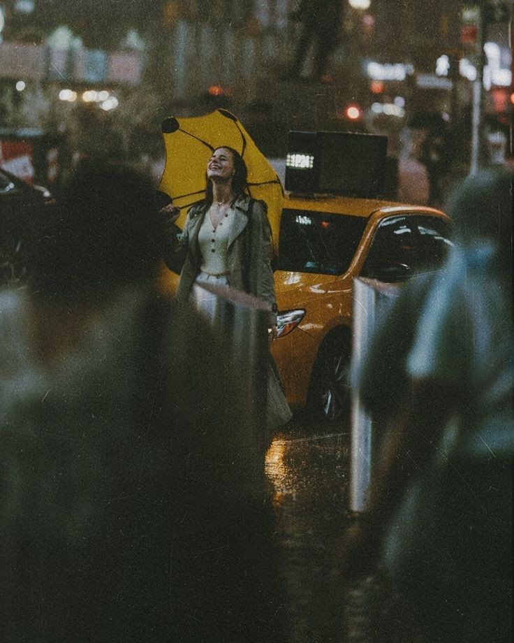 a woman holding an umbrella in the middle of a busy city street at night time