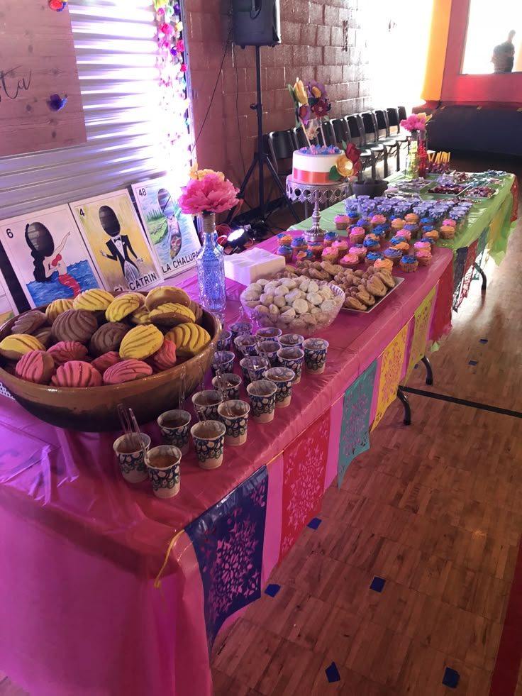 a table topped with lots of cupcakes next to a cake and candy bar