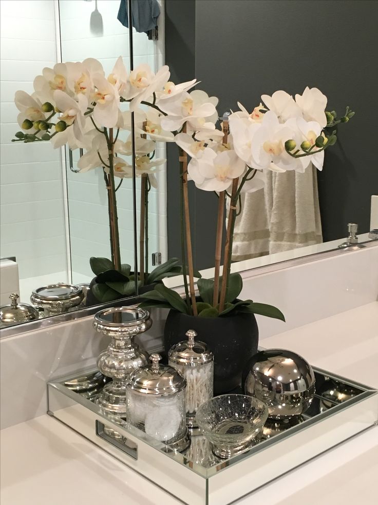 a bathroom sink with a mirror and some flowers in the vase on top of it