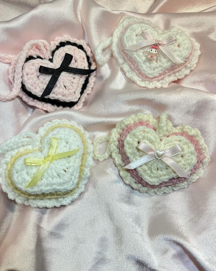 three crocheted heart shaped brooches laying on top of a white blanket