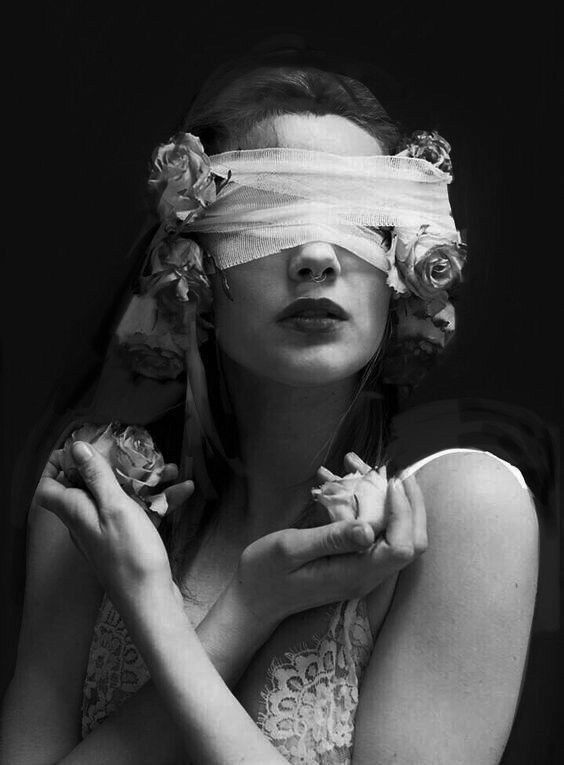 a woman with blindfold and flowers on her head is shown in this black and white photo