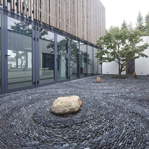 a large rock sitting on top of a gravel covered ground next to a tall building