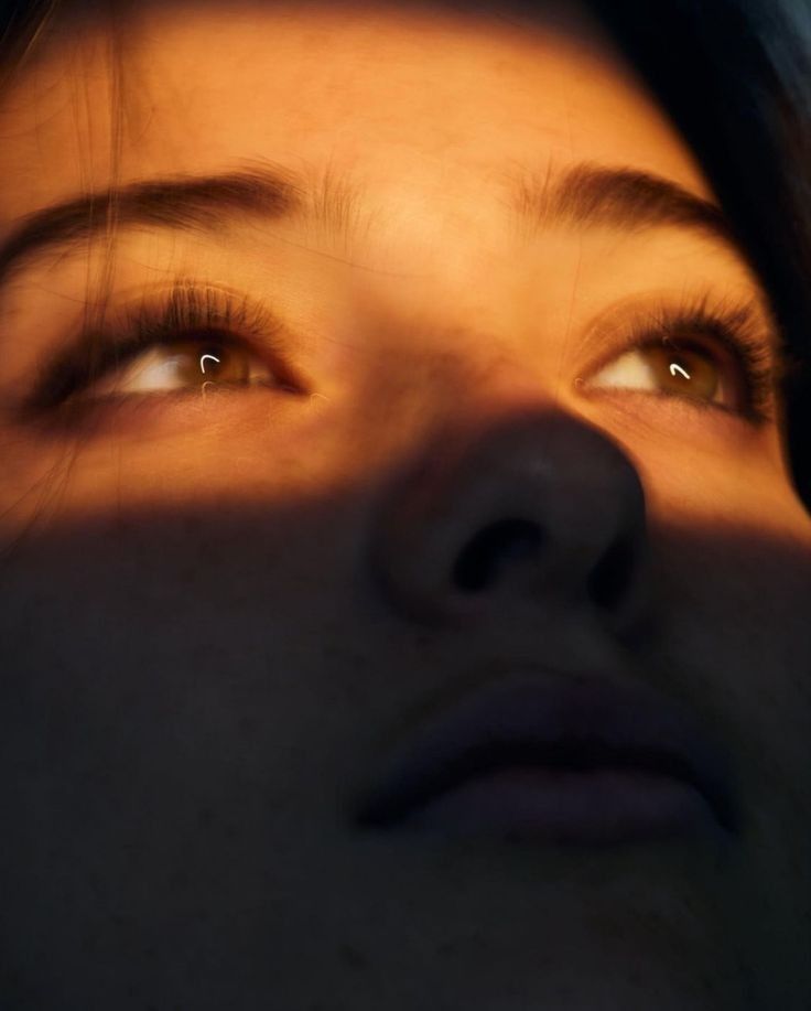 a close up of a woman's face with the sun shining through her eyes