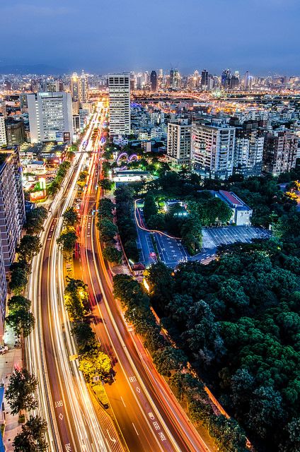 an aerial view of a city at night with long exposure lights on the streets and buildings