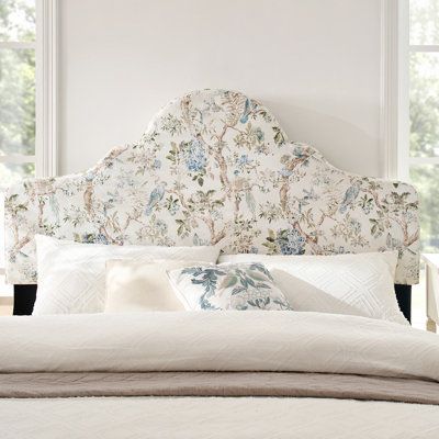 a white bed with floral headboard and pillows